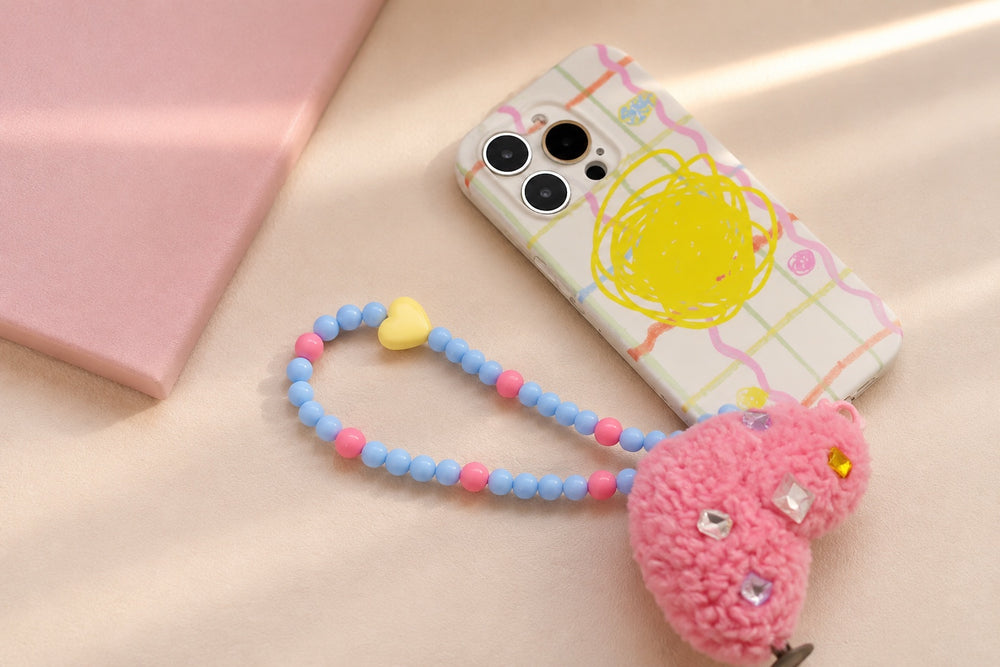 Blue and pink beaded phone wrist strap arranged with its phone case on a cream surface